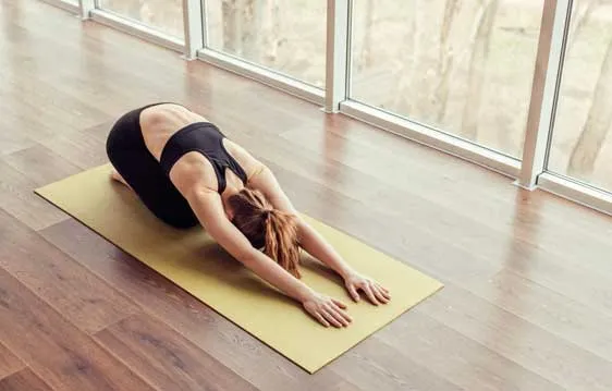 A woman resting in child's pose on a yoga mat